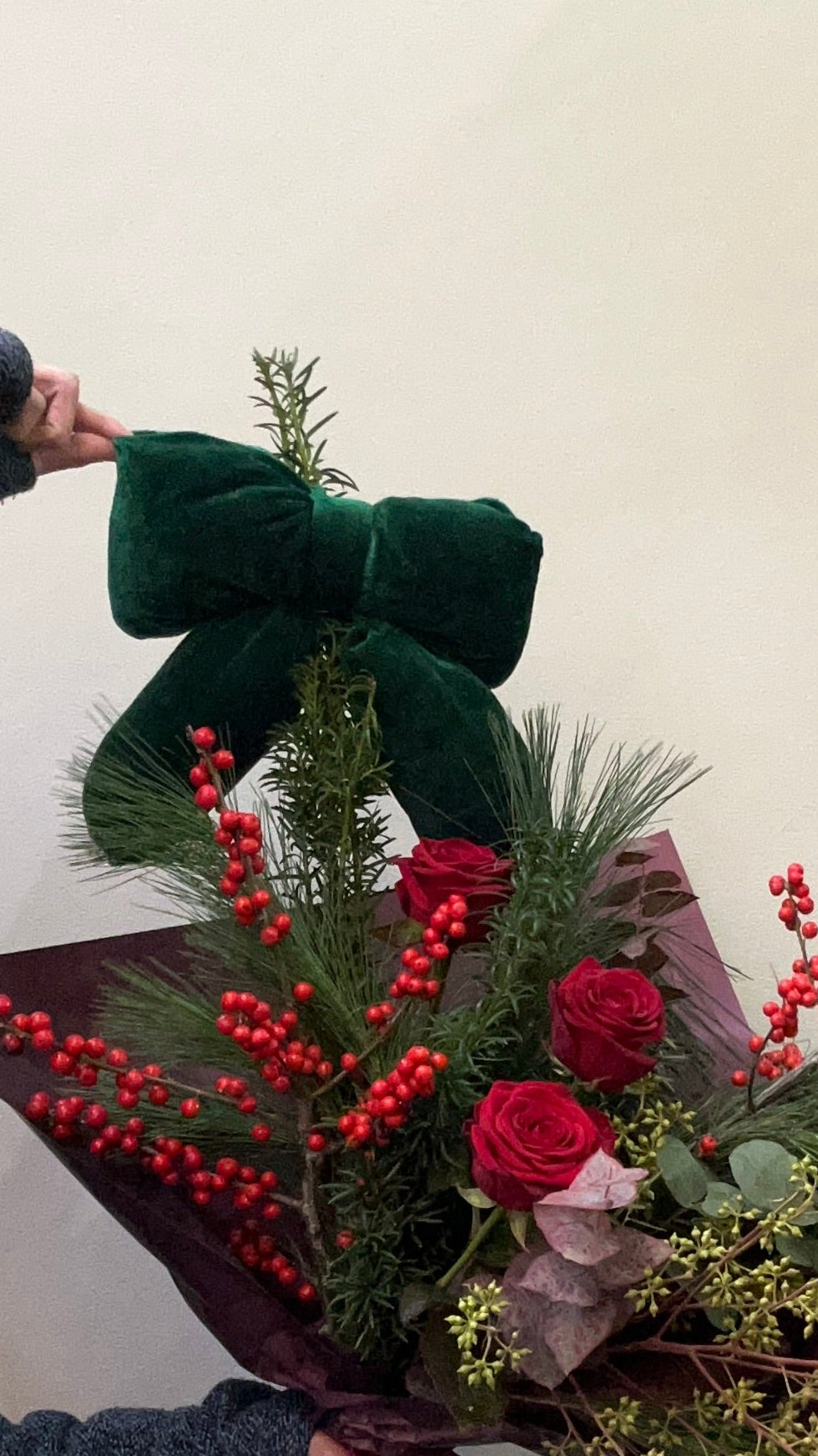Bouquet of flowers with a large green bow held by a person against a white background